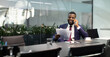 © Prostock-studio - Wealthy black guy in suit entrepreneur having phone conversation with his assistant or business partner, sitting at table with digital tablet on, looking at documents, panorama with copy space