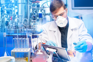 Poster - Man laboratory assistant. Scientist biologist in white coat. Laboratory assistant sits at table with tablet. Man scientist near bioreactor. Laboratory technician at workplace with test tubes