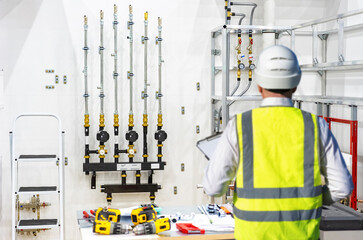 Poster - worker in room with utilities. installation of heating system in apartment. worker in yellow vest in