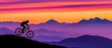 Silhouette of cyclist on mountain bike against vibrant sunset over layered mountain range