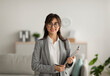 © Prostock-studio - Portrait of cheerful female psychologist posing with clipboard, looking and smiling at camera, working in modern office. Psychotherapy services, mental health professional concept