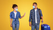 © Prostock-studio - Keep Social Distance During Travel. African Woman Gesturing Stop To A Tourist Standing With Luggage On Yellow Background In Studio, Wearing Protective Face Mask. Coronavirus Traveling Rules Concept
