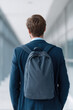 © SnowElf - A person in a suit is wearing a backpack, walking down a hallway with glass walls. The concept is business travel or professional mobility
