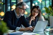 © soem - Two business professionals working together on a laptop in a modern office setting.