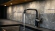 © aishale - Modern kitchen faucet with flowing water over dark gray stone.