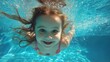 © AGI Studio - A young girl swims underwater in a pool, smiling joyfully at the camera with sunlight streaming through the water.