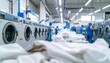 © youthe - Laundry facility shows workers using machines, with white textiles in the foreground