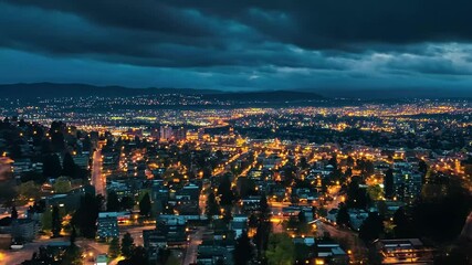 Poster - City lights illuminate the landscape in aerial drone shot at dusk, City lights from the sky aerial drone shot