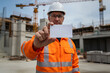 © LADALIDI - Construction worker engineer in orange safety suit holding blank business card at building site. branding, business identity, construction industry mockup