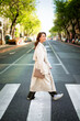 © sepy - Full length of an attractive brunette haired woman walking through the pedestraian crossing in city
