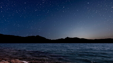Wall Mural - sunrise over the sea with gentle waves and fading stars in a peaceful, dreamy atmosphere