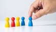 © photostockatinat - A hand picking a blue pawn from a group of colorful pawns, showcasing the concept of choice, selection, or decision-making.