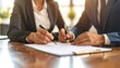 © Chatchawan - Businesspeople Reviewing and Signing Important Documents Together at a Desk