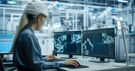 Fototapete - Caucasian Female Technician Working Behind a Desk in a Modern Product Development Factory, Using Industrial Computer Software on Displays, Monitoring Electronics Production Line with Robotic Arms