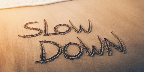 Poster - Sand texture beach background with the words Slow Down written in the sand near ocean waves, representing relaxation, peace, and mindful living