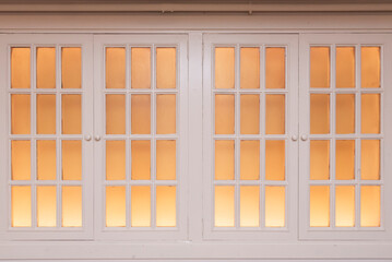 Poster - A white wooden French window with a soft orange light behind it