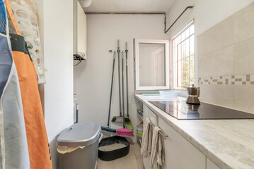 Poster - Corner of a kitchen with cleaning supplies hanging on the wall