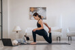 © standret - Laptop is on the floor. Woman with pug dog is doing yoga at home