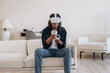 © standret - Modern controllers and headset. Black man in virtual reality glasses at home