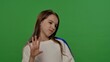 © kinomaster - Teenage girl posing at camera smiling and waving hand, positive expression, isolated on chroma key green screen studio background mockup.