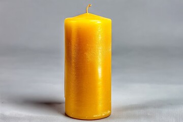 Aufkleber - Long yellow candle stands upright on a gray background creating a warm and inviting atmosphere for relaxation and ambiance