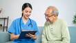 © Panarat - in a brightly lit room, an individual in a blue uniform, wearing a stethoscope, is seen holding a clipboard and pen while looking down at it with a gentle smile