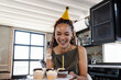 © Wavebreak Media - Woman holding plate of frosted cupcakes in home kitchen celebrating birthday with sparkler