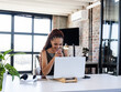 © Wavebreak Media - Woman working on silver laptop on stand in modern office, with notebook plant headphones