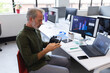 © Wavebreak Media - Senior man inspecting VR headset at office desk, with monitors and coffee, copy space