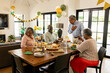 © WavebreakMediaMicro - Family celebrating together at home, enjoying food and laughter around dining table