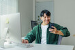 © Crystal - Happy young man working remotely using desktop computer and smartphone, typing on keyboard and looking at mobile phone screen