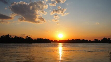 Poster - Witness captivating transformation as sun gracefully sinks below horizon over Sava River. Time lapse sunset. Vivid colors dance across sky, silhouettes of trees. Stunning backdrop. Serbia at spring.