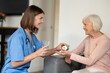 © zinkevych - Nurse in uniform offering health support and nursing care to elderly patient in retirement home