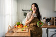© Kawee - Asian attractive woman eatting green healthy salad in kitchen at home.