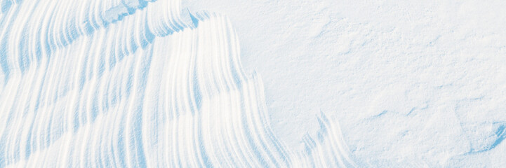 Wall Mural - wide panoramic winter background with snowy ground. natural snow texture. wind sculpted patterns on 