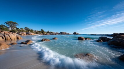 Poster - Rugged coastline showcases smooth grey stones washed by turquoise waves, with a vibrant sky enhancing the tranquil yet dynamic atmosphere of the location