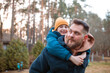 © Natallia - Lifestyle photo of bearded dad holding smiling boy on his back hugging him. Father and son spending time together outdoors. Family value, father's love and support, father's day. Selective focus