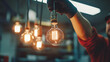 © Velem - Hand Holding a Vintage Edison Light Bulb in an Industrial Setting