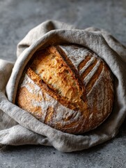 Aufkleber - Freshly Baked Sourdough Loaf Wrapped in Linen on a Rustic Surface Showcasing Its Crusty Exterior and Airy Interior