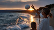 © Lumos Studio - Woman and child playing with a ball on a beach during sunset time