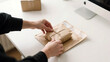 © linzette - Hands Preparing a Small Package for Sustainable Shipping