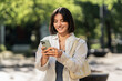 © Andrei - A summer day out. A smiling woman checking an app on her phone in the city. Browsing online shops, chatting with friends and family or checking the map for navigation