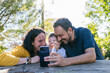© ADDICTIVE STOCK - Family taking a joyful selfie outdoors in a sunny park setting