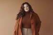 © CreativeLight - A stylish woman with long wavy hair wearing a brown turtleneck and an oversized coat posing against a warm toned background