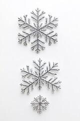 Poster - Three Silver Glitter Snowflakes Arranged Vertically on White Background Flat Lay Winter Holiday Season Decoration