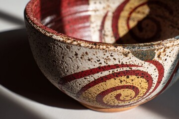 Poster - Ceramic bowl with intricate spiral design showcasing vibrant colors and texture on a sunny surface