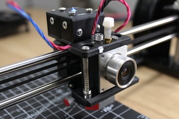 Poster - Close-up view of a 3D printer hotend assembly with wiring and components in a workshop environment during daytime