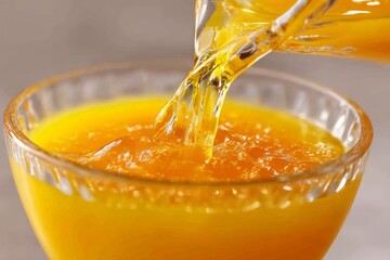Poster - Refreshing orange juice is being poured into a glass with a vibrant color in a bright kitchen setting