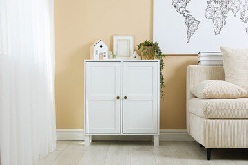 Poster - Dresser with stylish decor and houseplant near beige wall indoors
