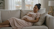 © nadialia - Serene expectant mother resting indoors on her comfortable sofa at home